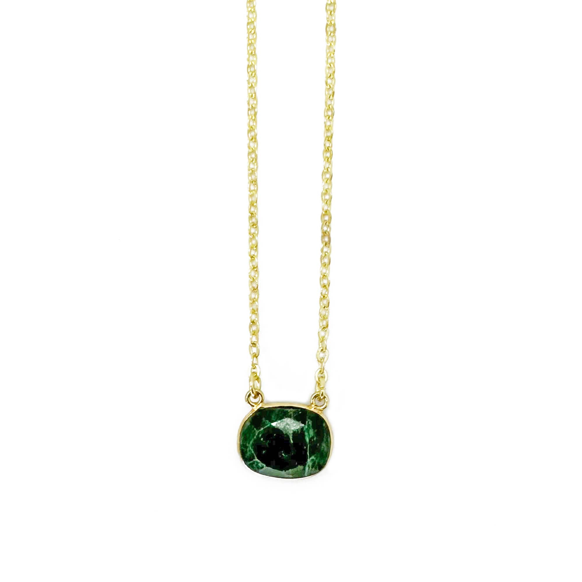 Gold necklace with a green gemstone pendant on a white background
